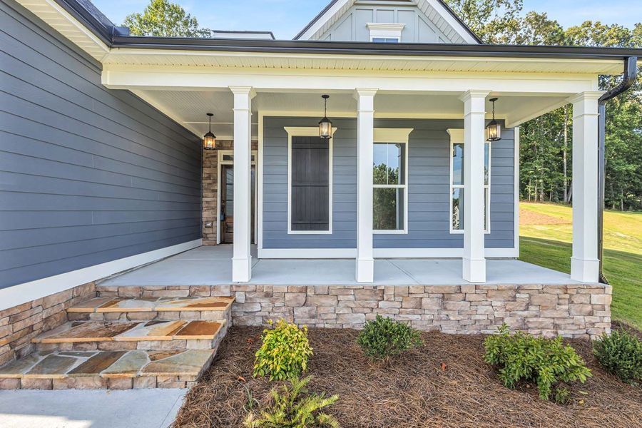Blue house with porch, stone steps, and landscaping.