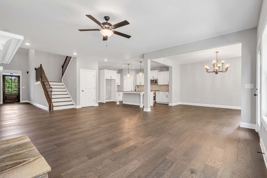 Spacious, light-filled interior with hardwood floors, a staircase, and an open kitchen.