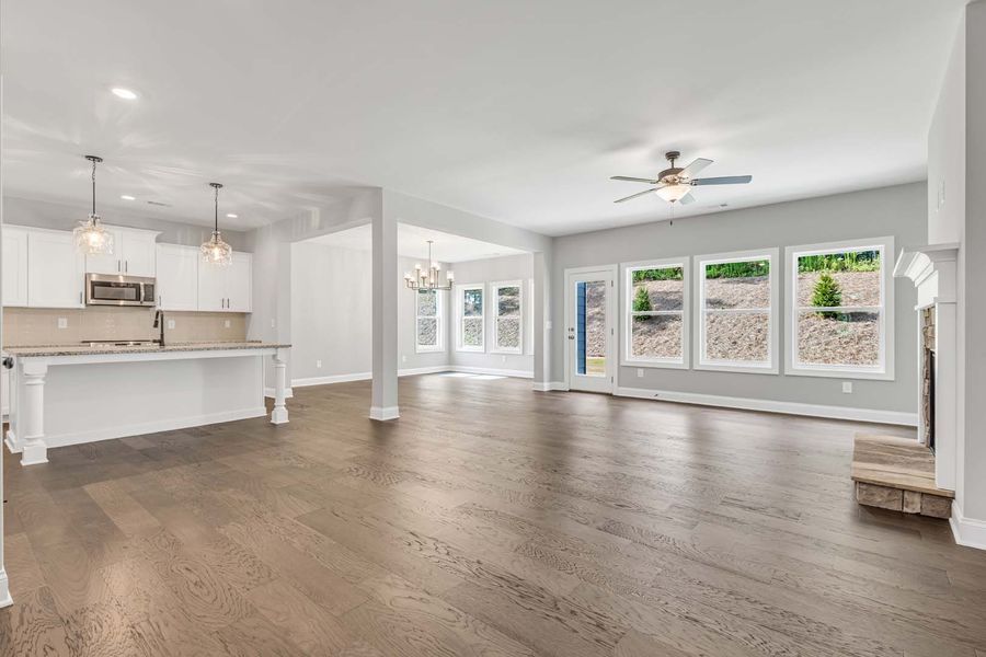 Open concept living area with kitchen, hardwood floors, and large windows.