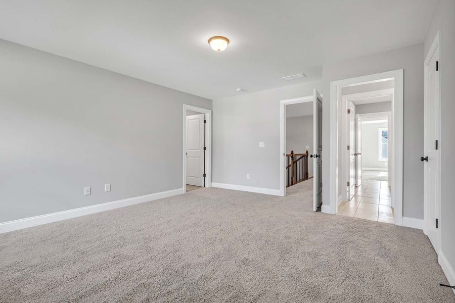 Empty bedroom with gray walls, carpet, and multiple doorways.
