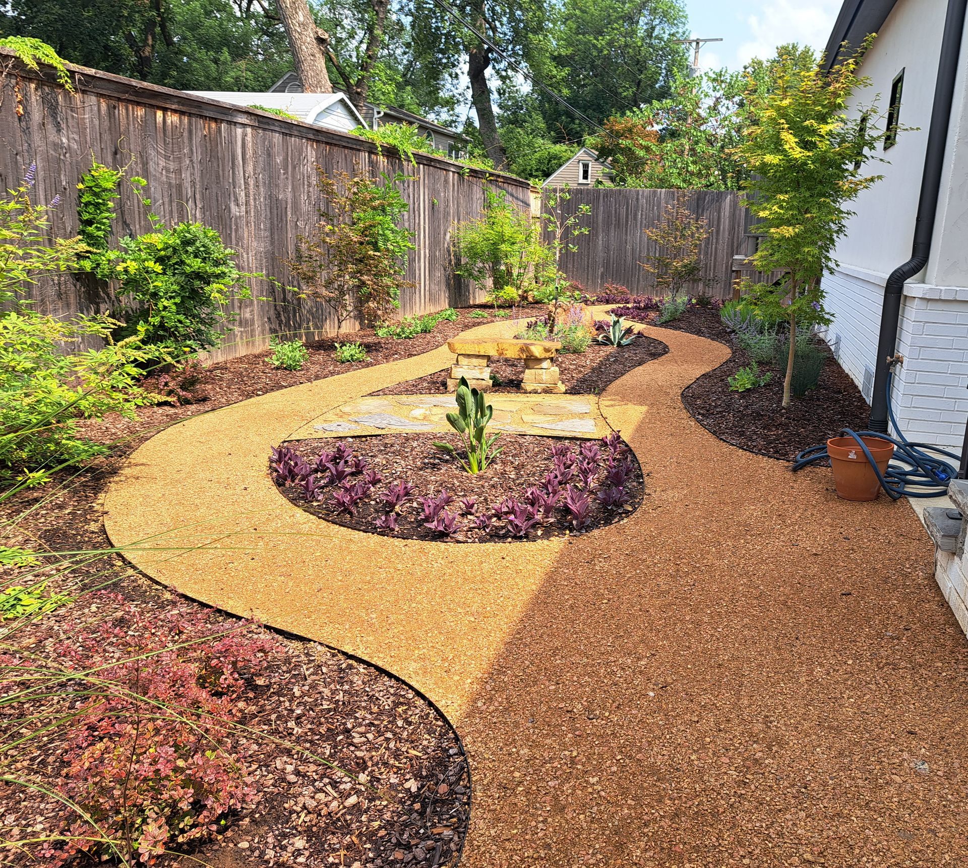 A garden with a path and a fence in the background.