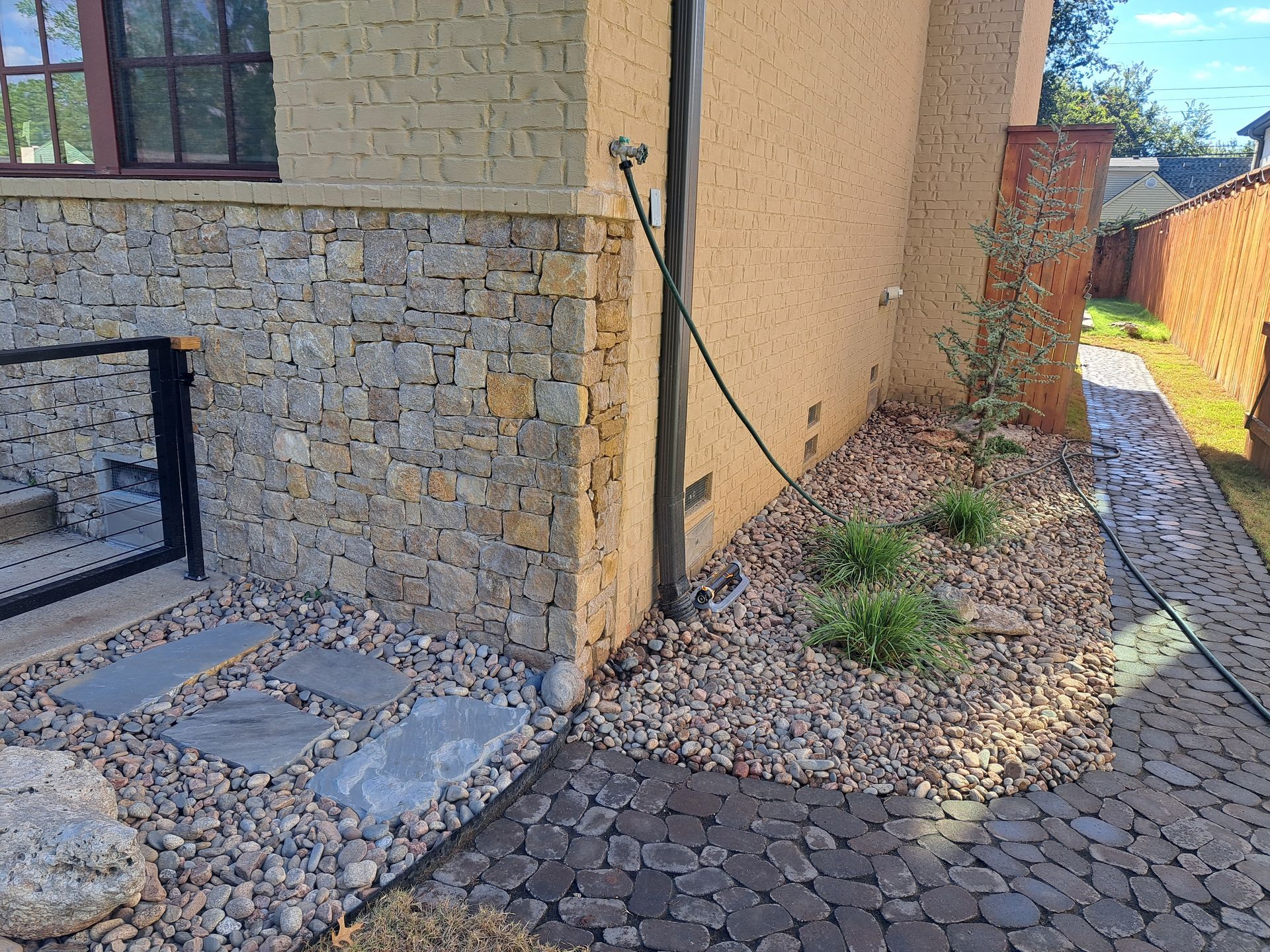 A hose is connected to the side of a brick building.
