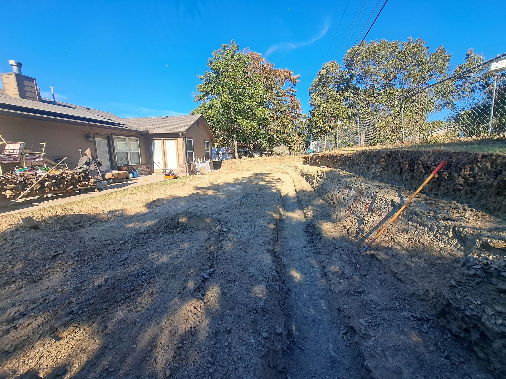 A dirt road leading to a house with a shovel in the dirt.