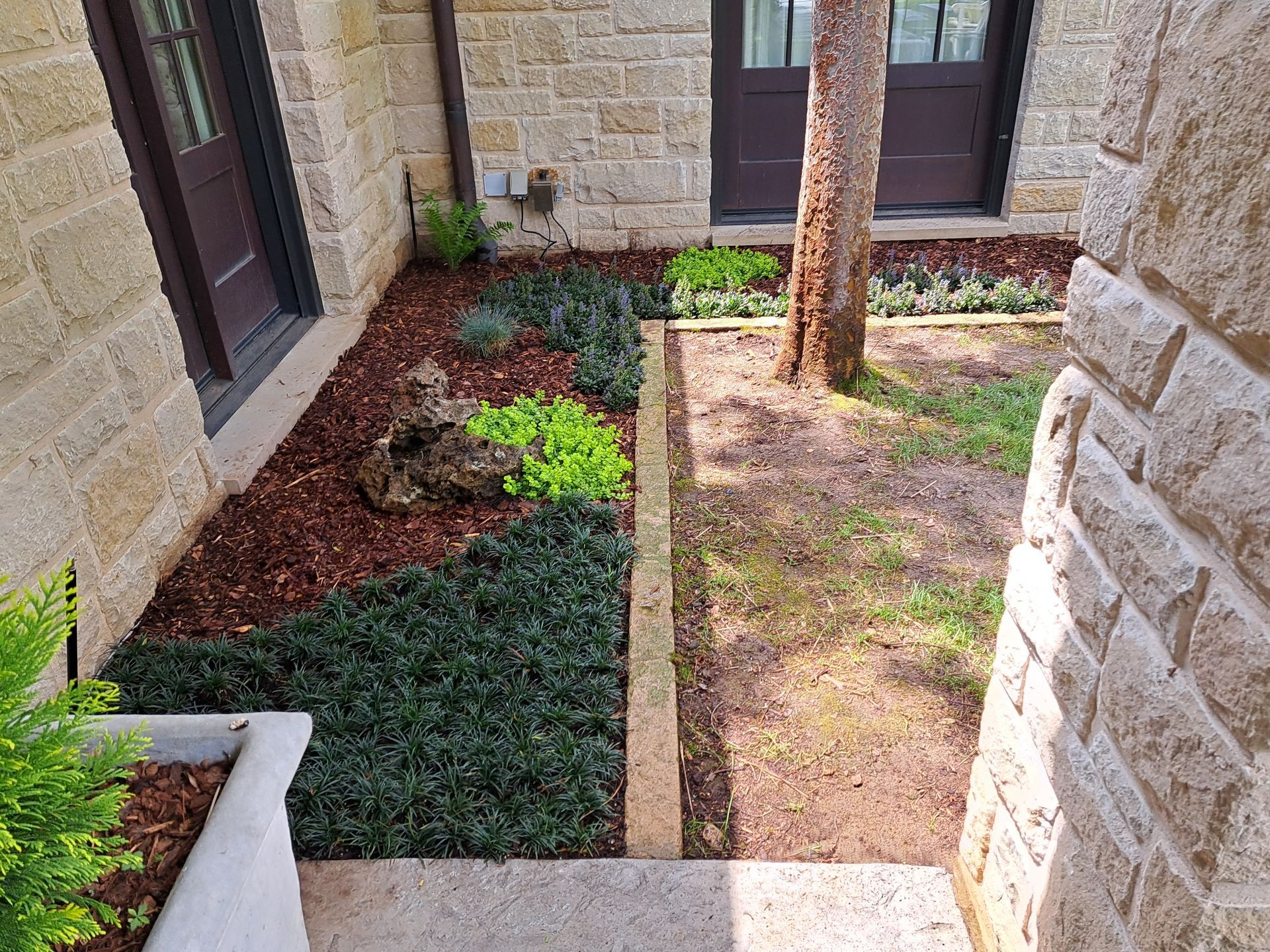 A brick building with a lush green garden in front of it.