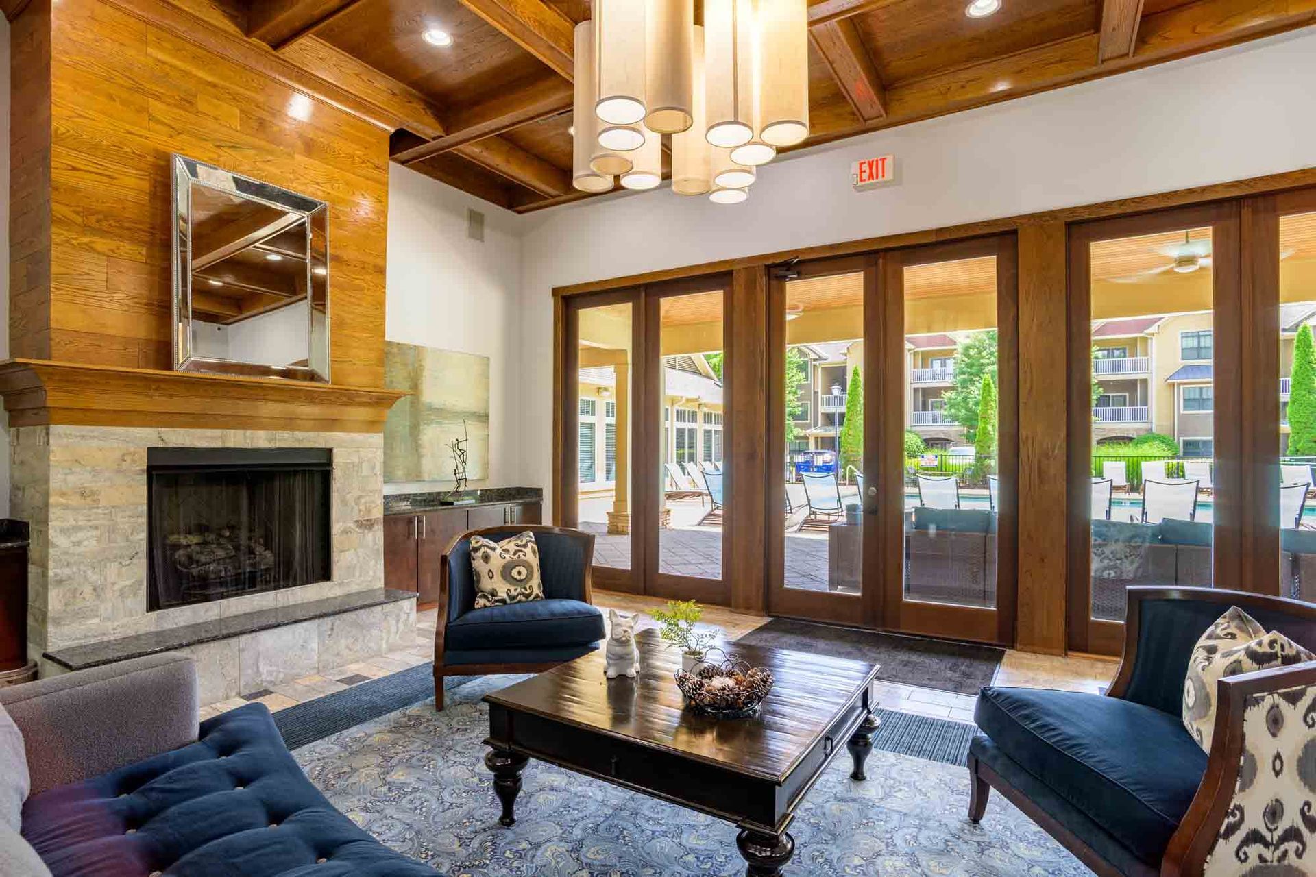 A luxurious lounge with fireplace, dark blue seating, and doors leading to an outdoor patio.