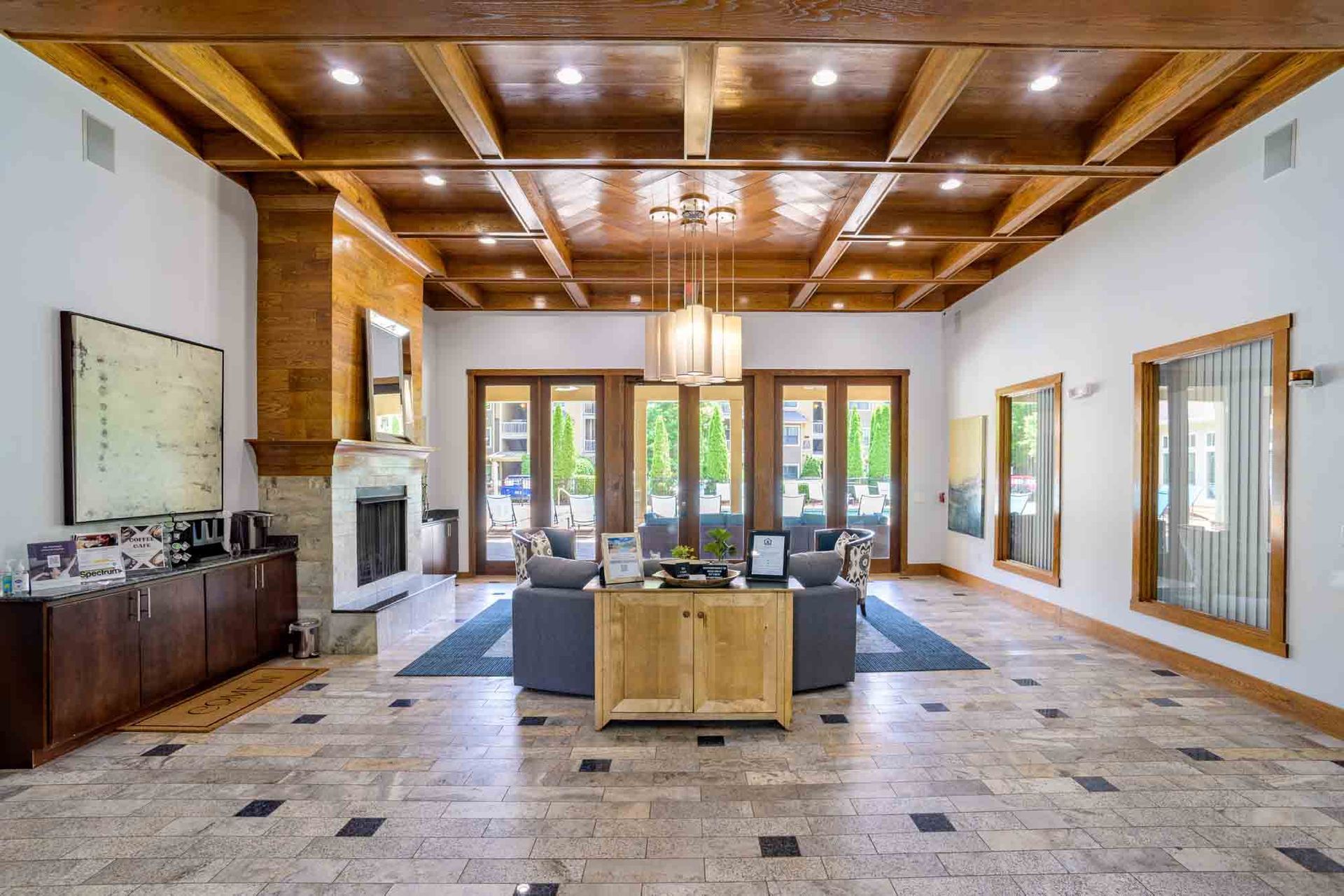 Lobby with stone floor, wood ceiling, fireplace, and doors leading to an outdoor patio.