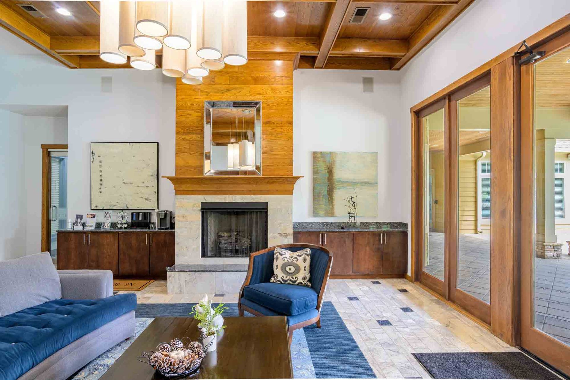 Luxurious living room with fireplace, blue sofa, wood accents, and glass doors.