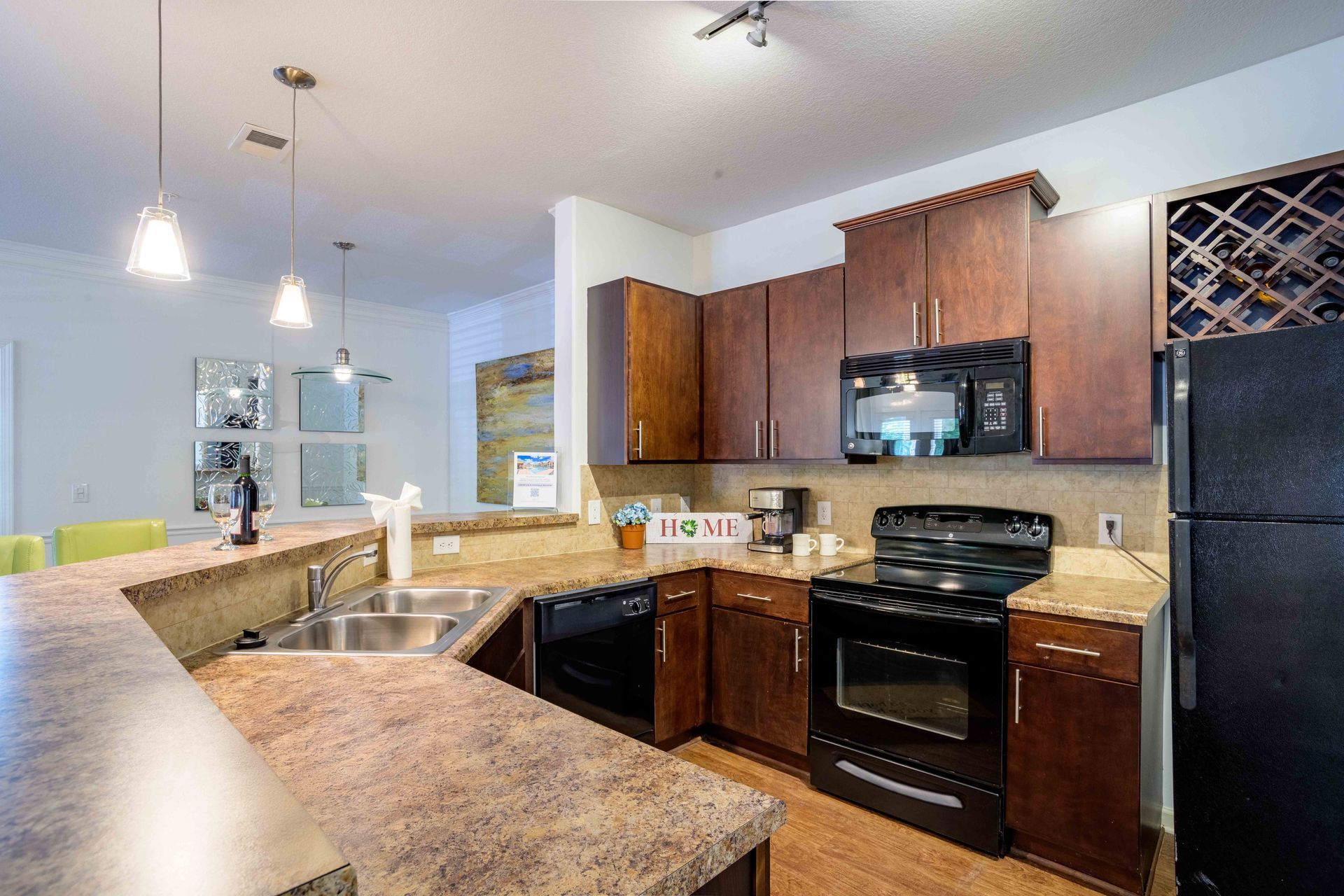 Kitchen with dark wood cabinets, appliances, and countertop. A view of an open floor plan.