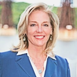 A woman in a blue jacket and white shirt is smiling for the camera.