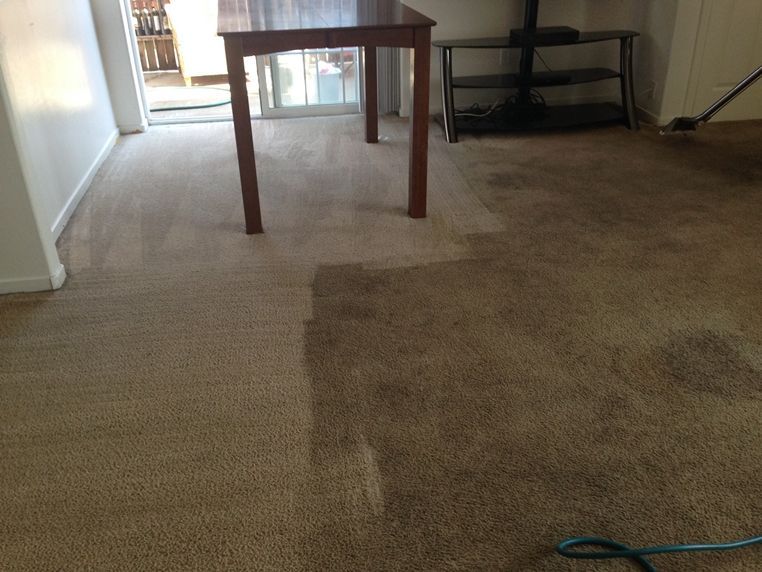 A carpeted floor with a wooden table in the background