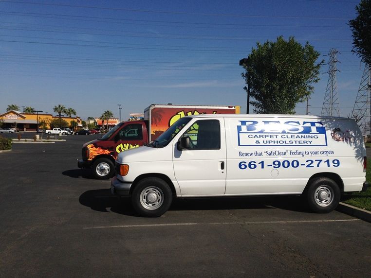 Two carpet cleaning vans are parked in a parking lot