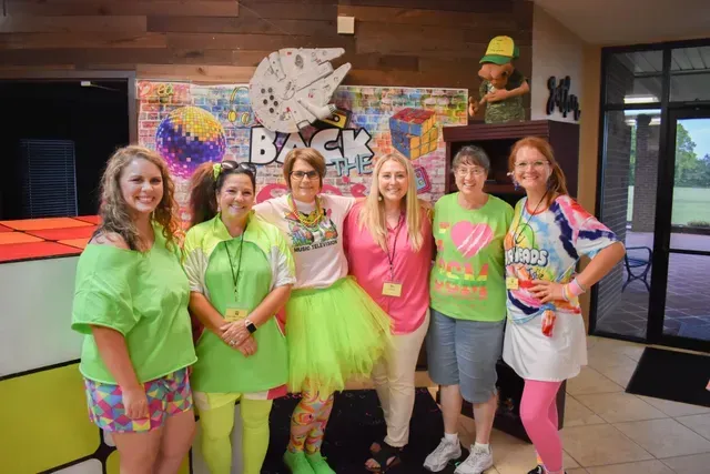 A group of women are posing for a picture in neon clothes.