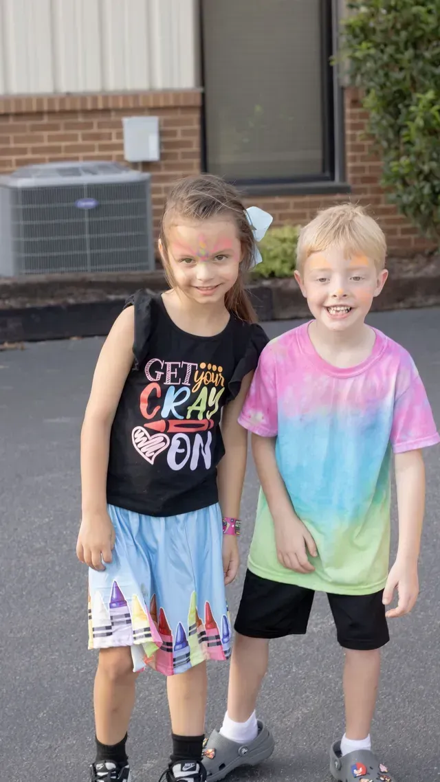 A boy and a girl are standing next to each other in front of a building.