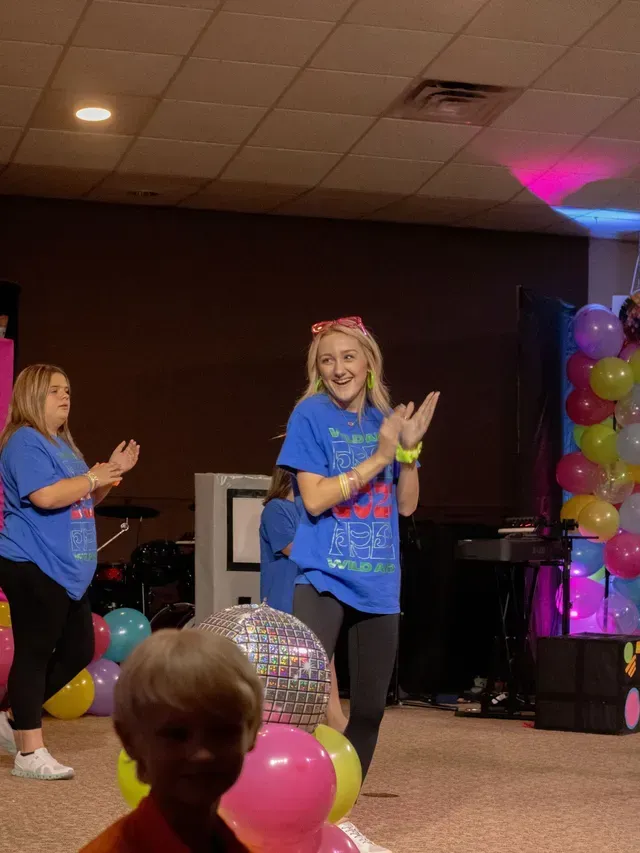 A group of people are dancing in a room with balloons.