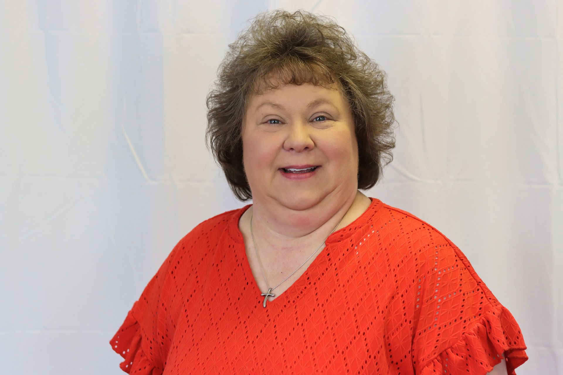 A woman in a red shirt is smiling for the camera.