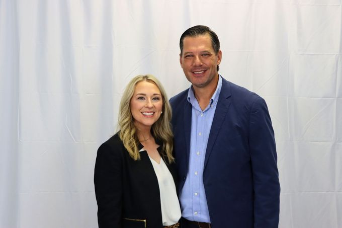 A man and a woman are posing for a picture in front of a white curtain.