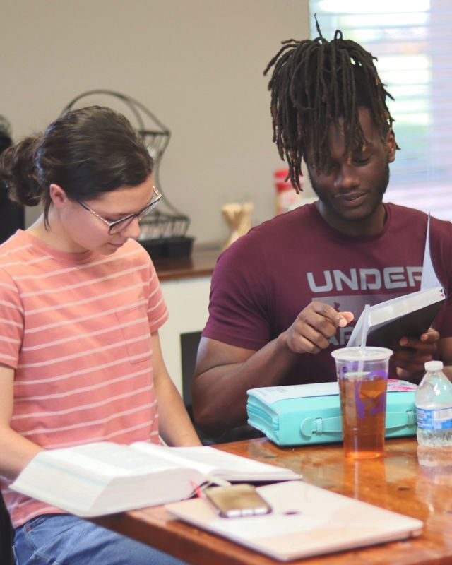 A man wearing an under armour shirt is reading a book