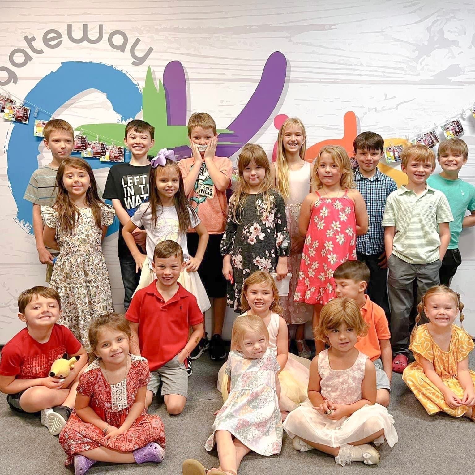 A group of children are posing for a picture in front of a sign that says gateway.