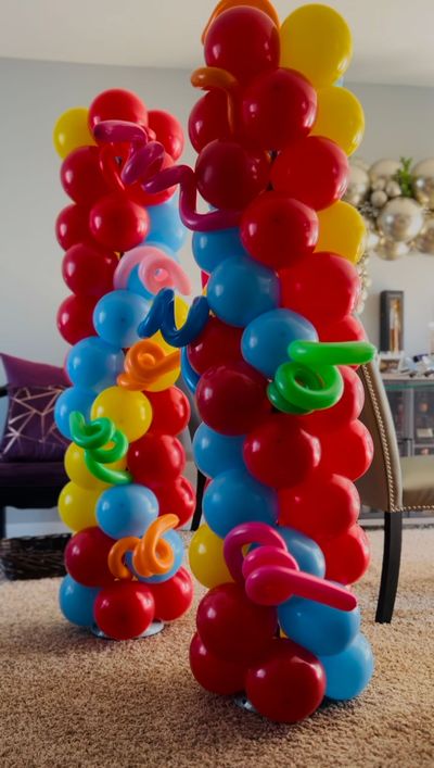 A bunch of colorful balloons are stacked on top of each other in a living room.