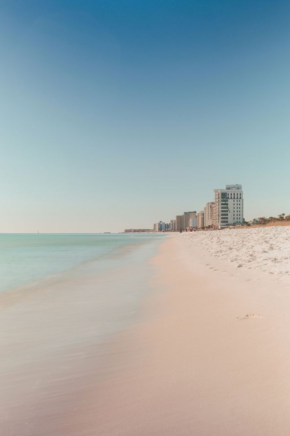 A beach with a lot of people on it and a building in the distance.