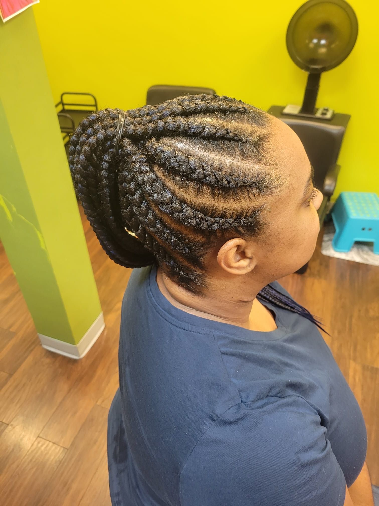 A woman with braids in her hair is wearing a blue shirt.