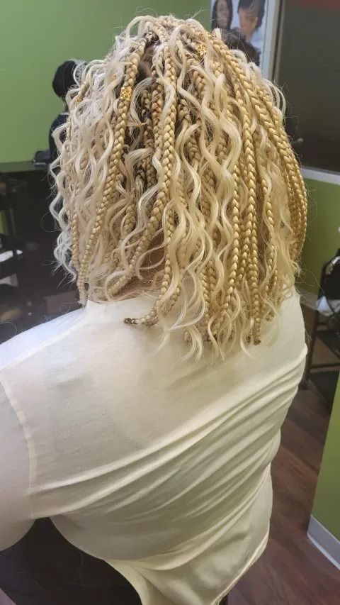 A woman with blonde braids and curly hair is sitting in a chair.