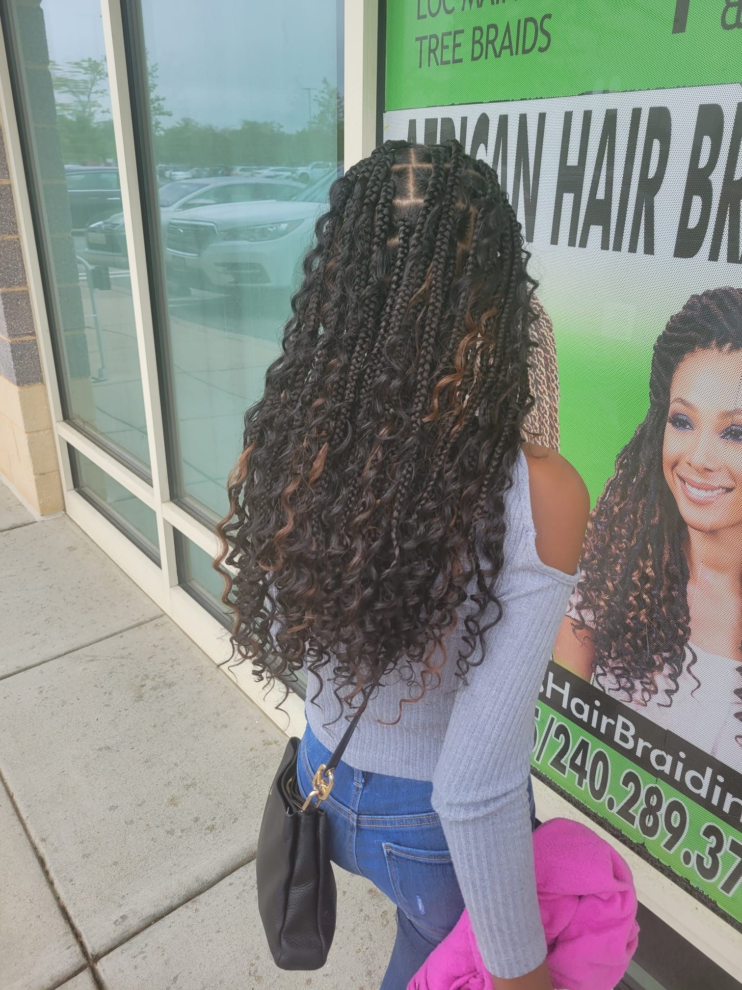 A woman with curly hair is standing in front of a building.