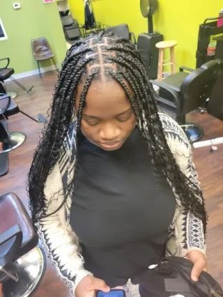 A woman with braids is looking at her phone in a salon.