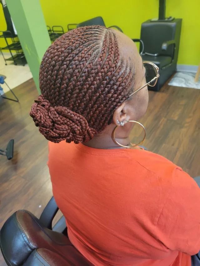 A woman with braids and hoop earrings is sitting in a chair.