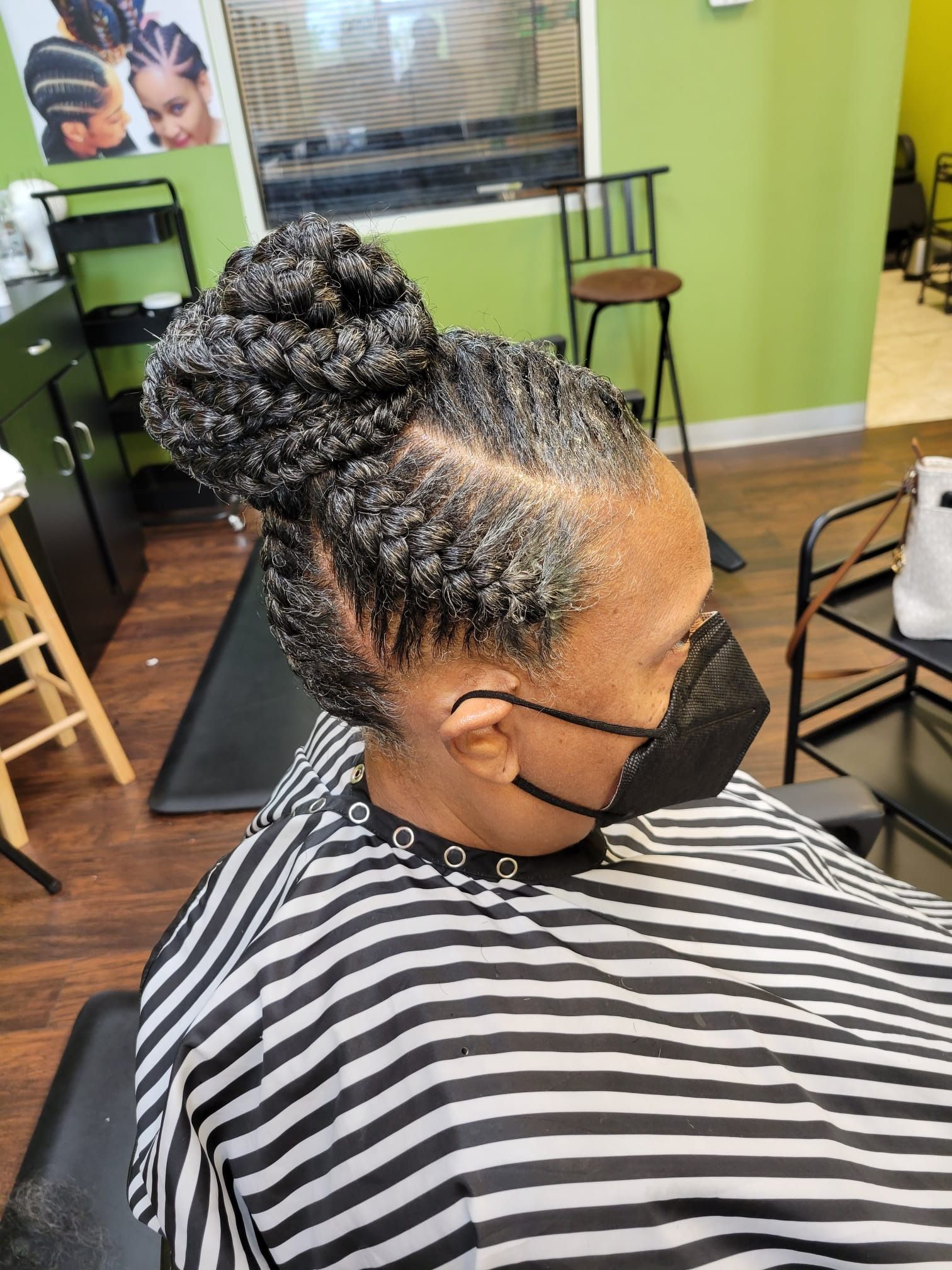 A woman wearing a mask is getting her hair done in a salon.