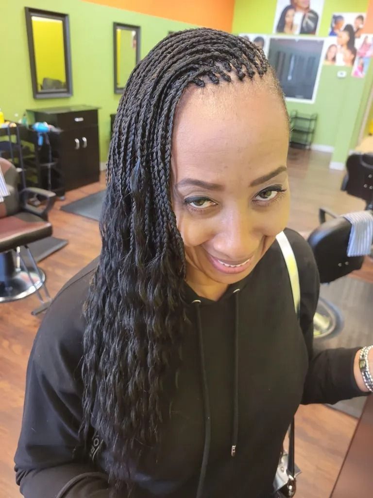 A woman with braids is smiling in a salon.