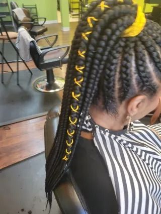 A woman is getting her hair braided in a salon.