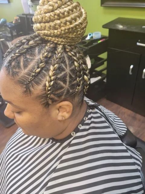 A woman is getting her hair braided in a bun in a salon.