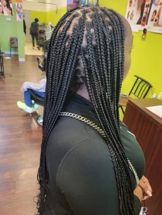 A woman with braids in her hair is standing in a salon.