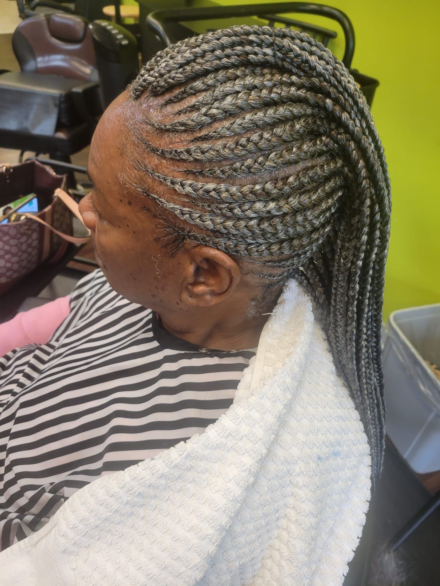 A woman is getting her hair braided in a salon.