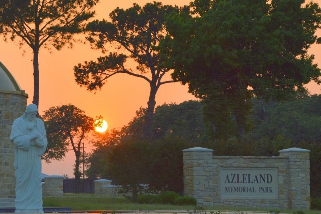 Sunset at Azleland Memorial Park with statue and sign.