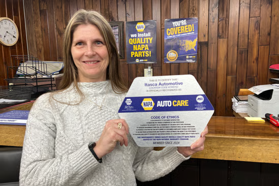 A person holing a NAPA Auto Care Code of Ethics | Itasca Automotive