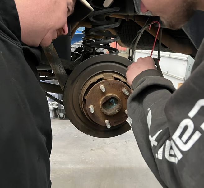 Mechanics working on a part of a car |  Itasca Automotive