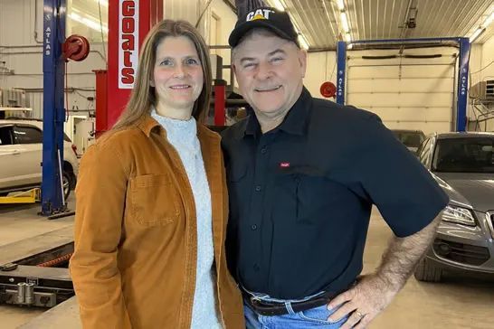Woman and man smiling in a garage. | Itasca Automotive