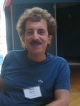 A man with a mustache is wearing a blue shirt and a name tag.