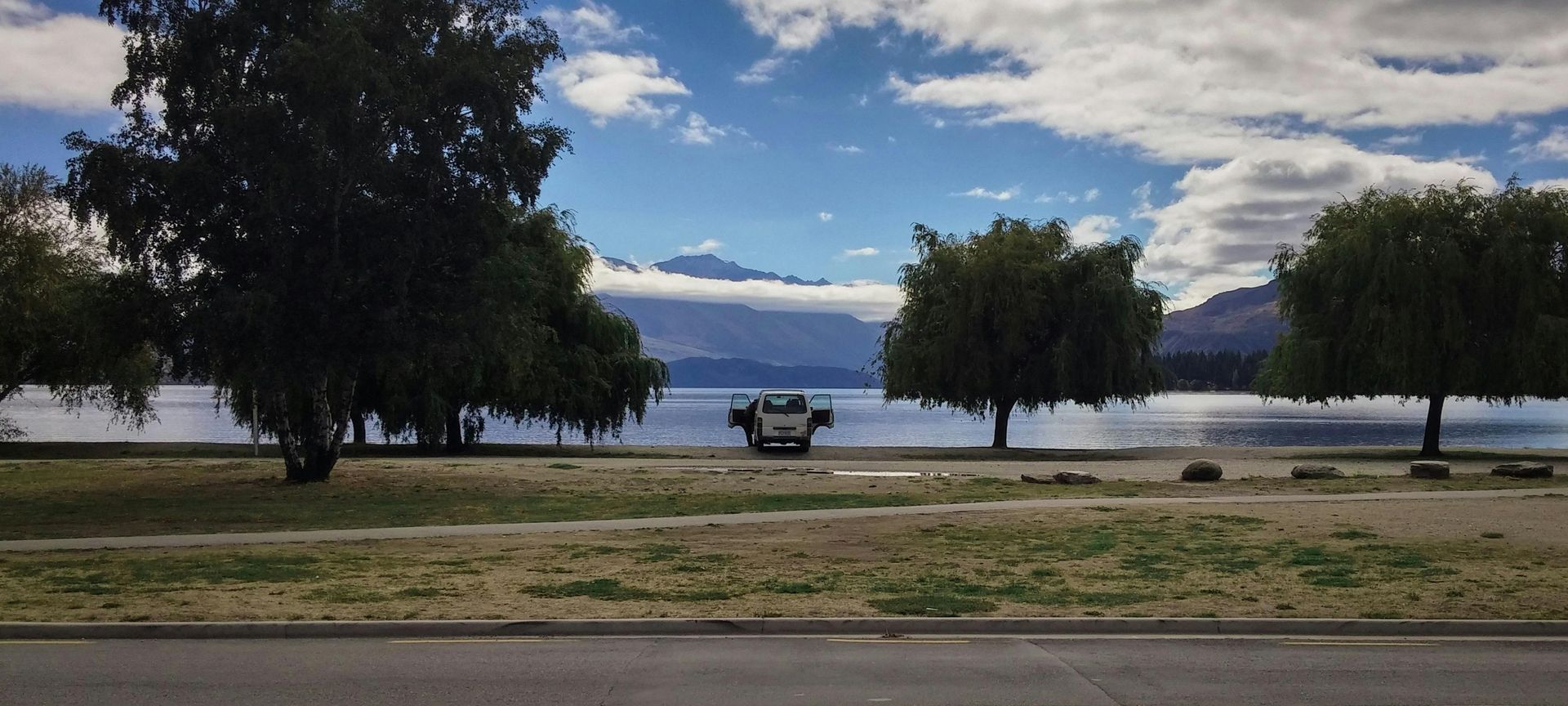 A park with trees and a lake in the background