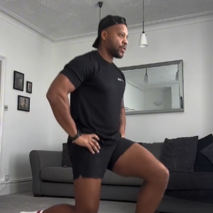 Man in black workout gear doing a lunge in a living room.