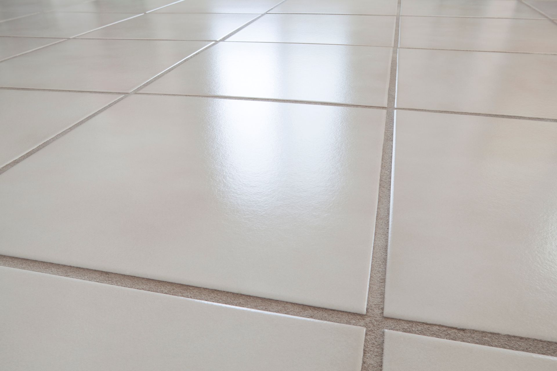 A man is cleaning a tile floor with a vacuum cleaner.