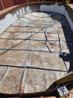 Empty in-ground pool being renovated, with concrete and framing visible.