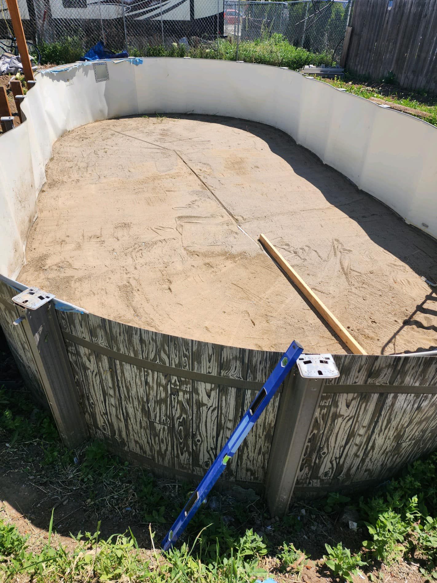 Above-ground pool under construction; earth floor, curved walls, level on side.