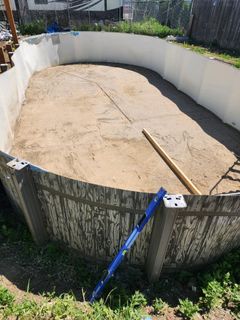Above-ground pool under construction; earth floor, curved walls, level on side.