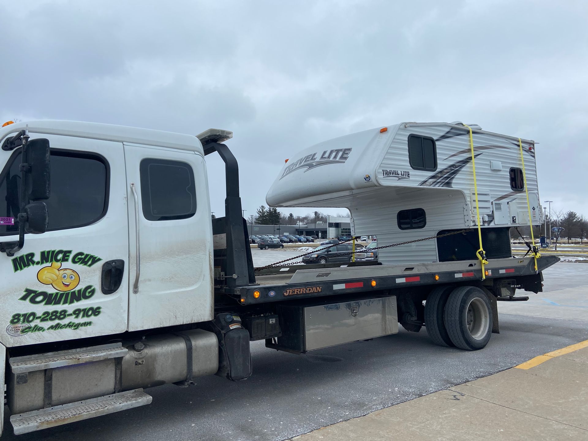 A tow truck is carrying a camper on the back of it.