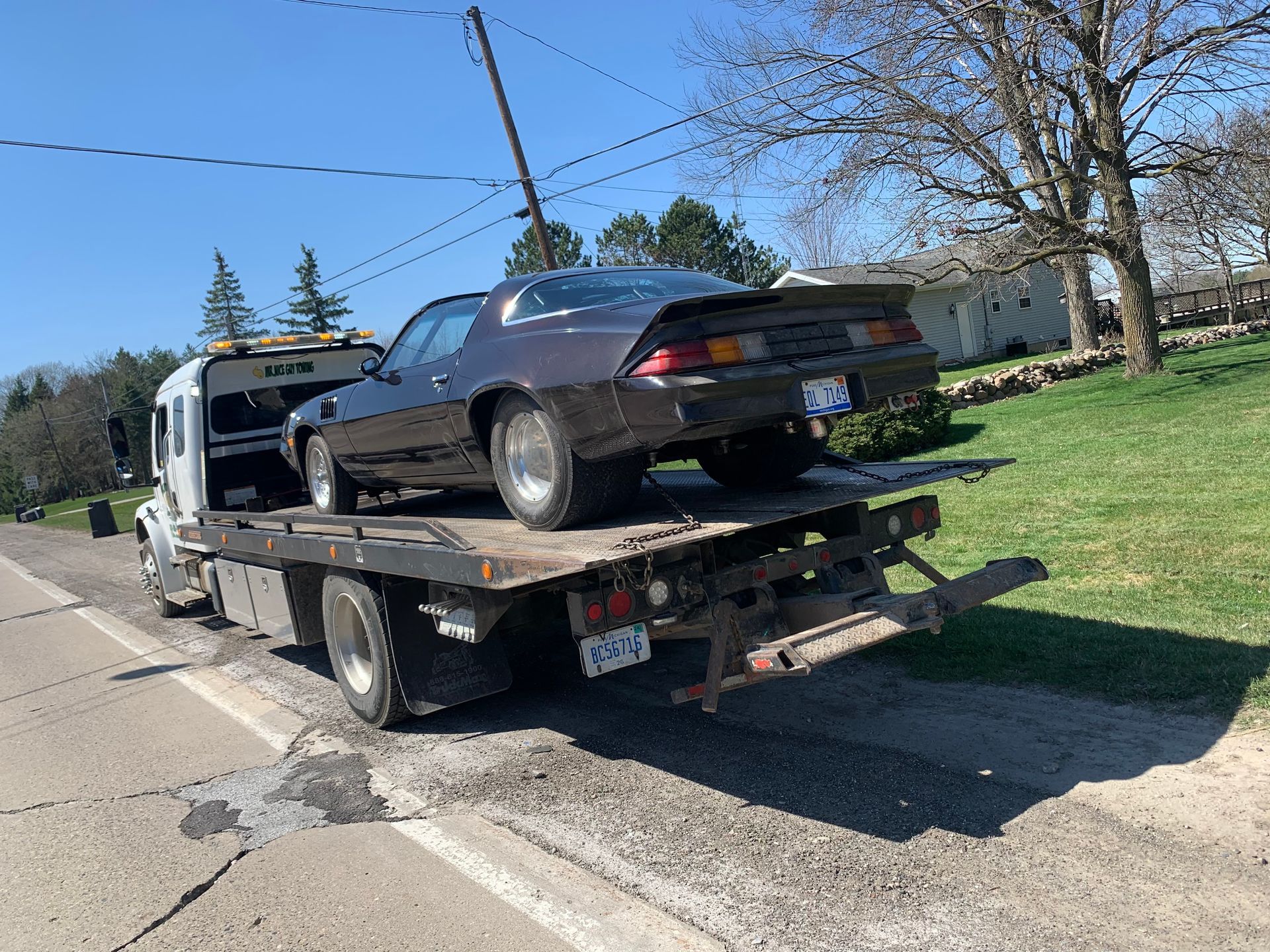 A black car is sitting on top of a tow truck.