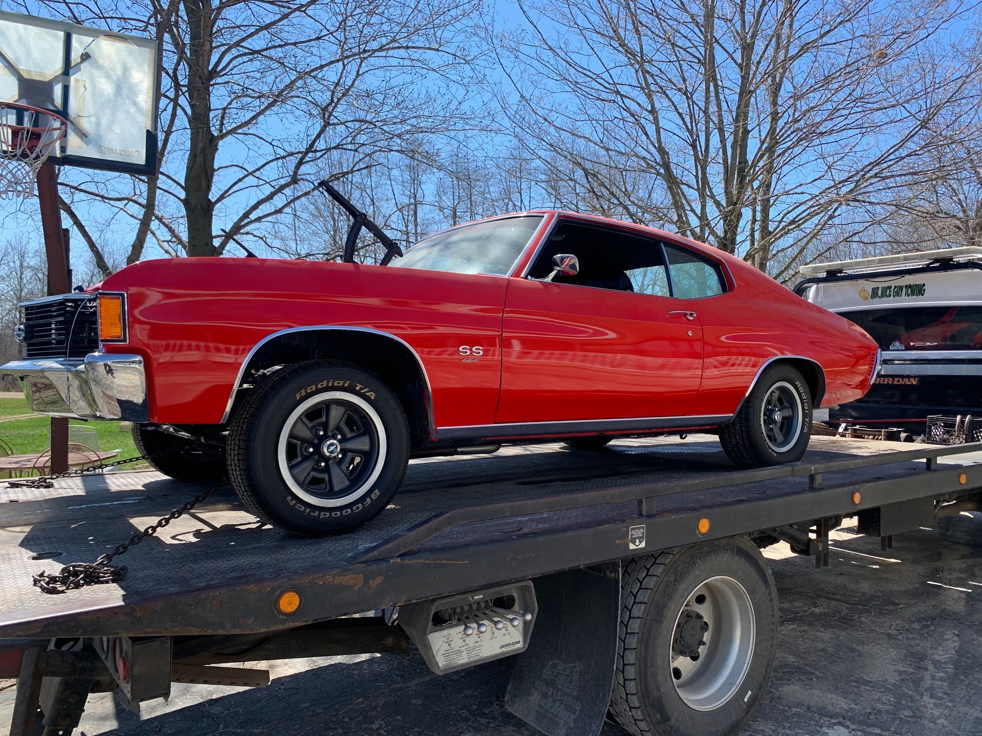 A red car is sitting on top of a tow truck.