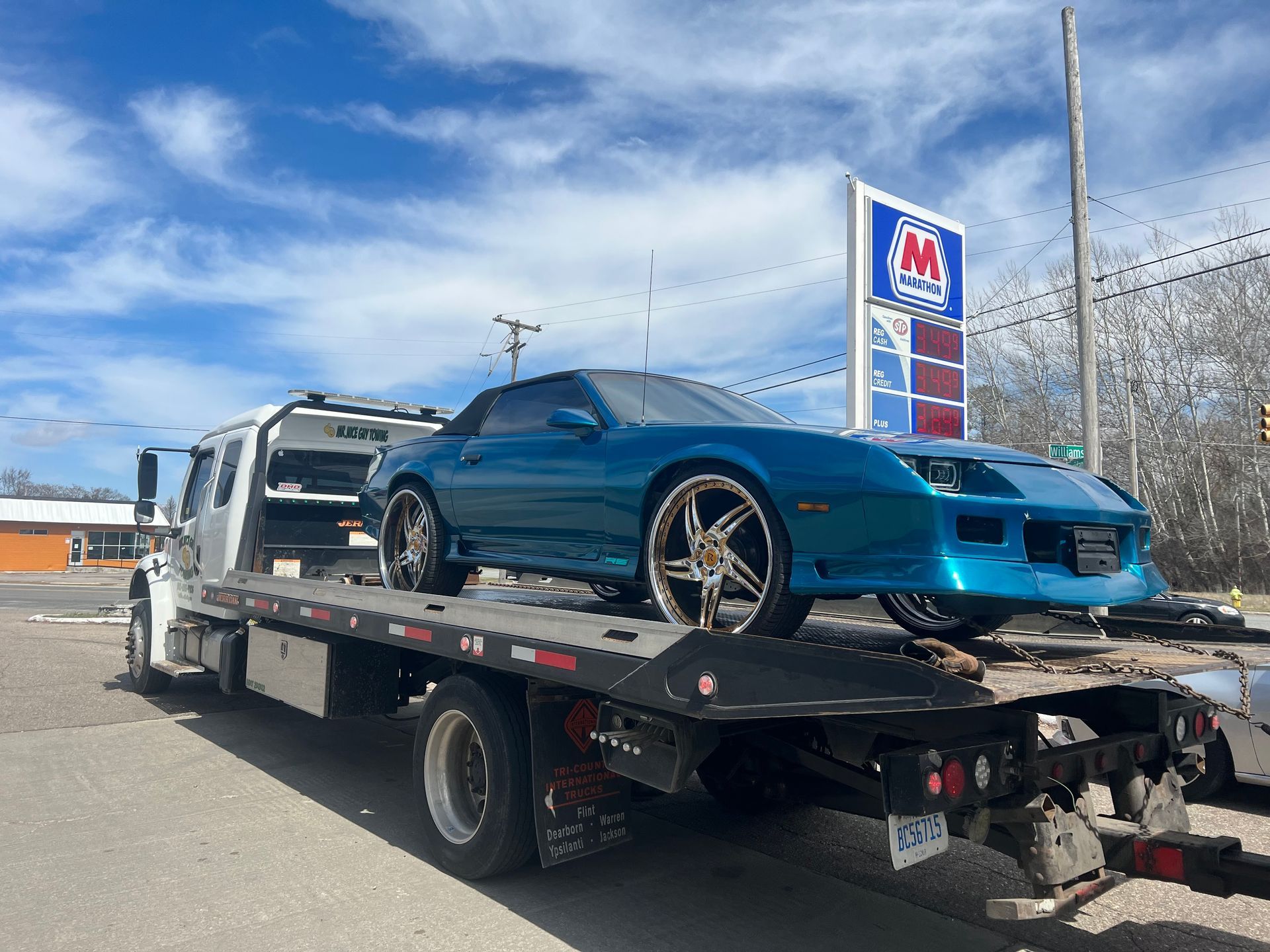 A blue car is being towed by a tow truck.